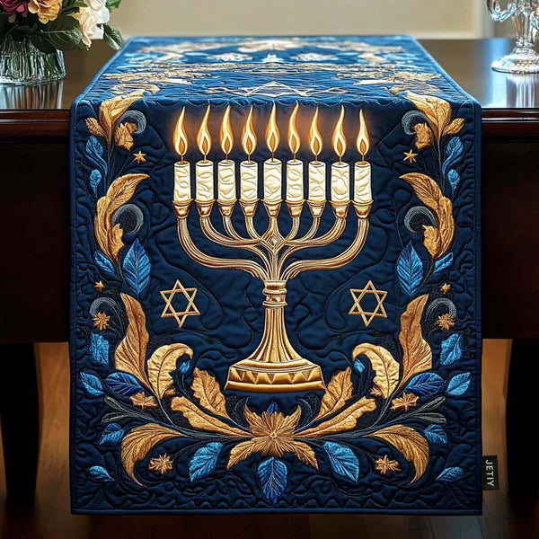 Quilted table runner with a lit golden menorah on a deep background laid down the centre of a table