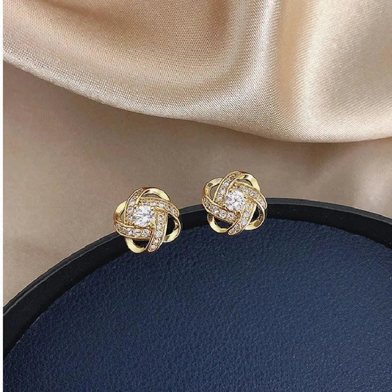 Gold-tone love knot stud earrings with a clear crystal