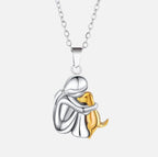 Silver-tone pendant of a woman hugging a gold dog