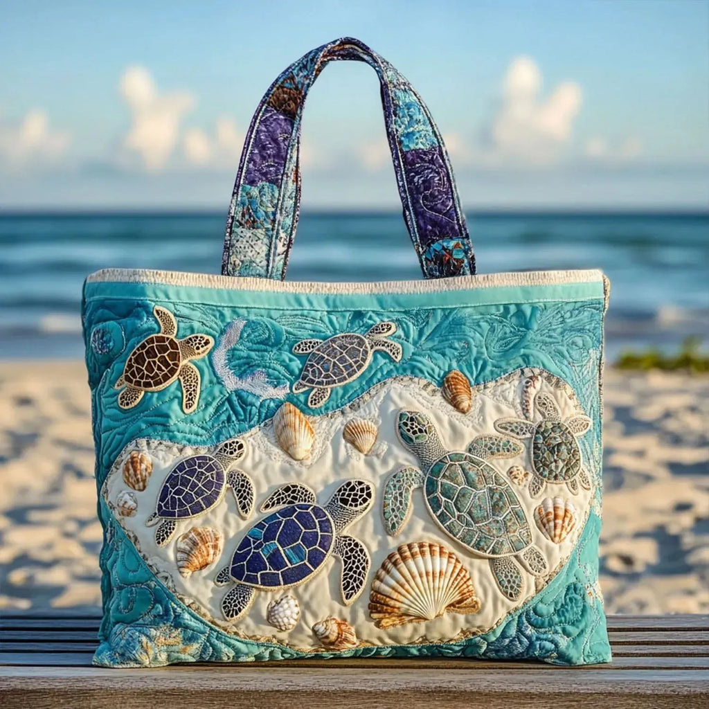 Artisan quilted tote bag with the Turtle Love design, two sea turtles swimming side by side, shells patterned in gold and coral against blue-green water