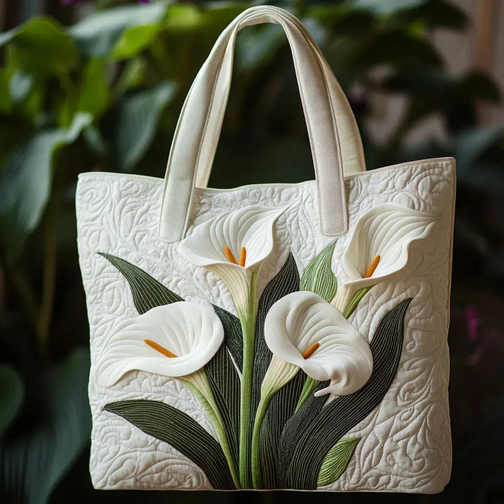 Artisan quilted tote bag with white lily blooms and slim green stems stitched in ivory across the front panel