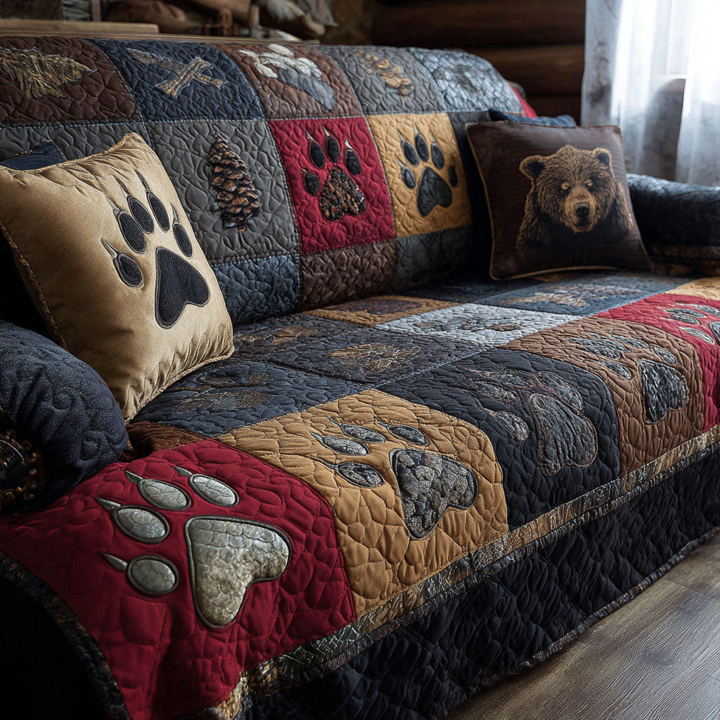 Bear Paw Cabin quilted sofa cover with barn red, navy, gold and slate blocks carrying bear paw prints and pinecone panels