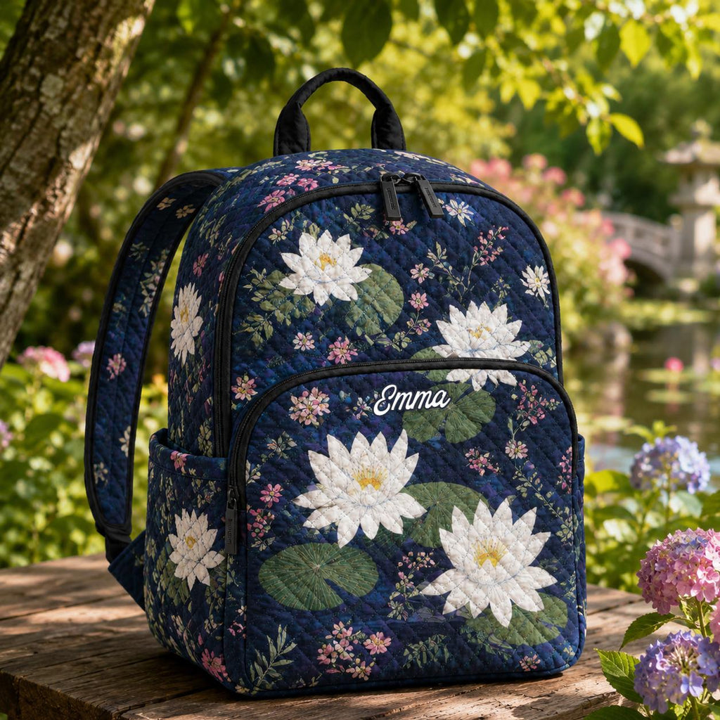 Artisan quilted backpack with water lilies opening across still water in pale petals and green pads