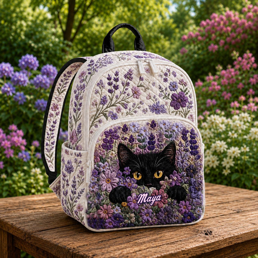 Artisan quilted backpack with a black cat sitting amongst tall purple lavender across the quilted front panel