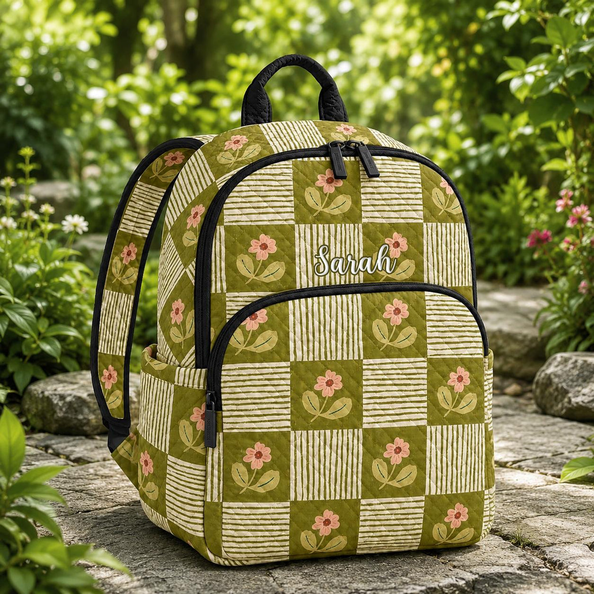 Artisan quilted backpack with white daisies scattered across green patchwork squares in mixed floral prints