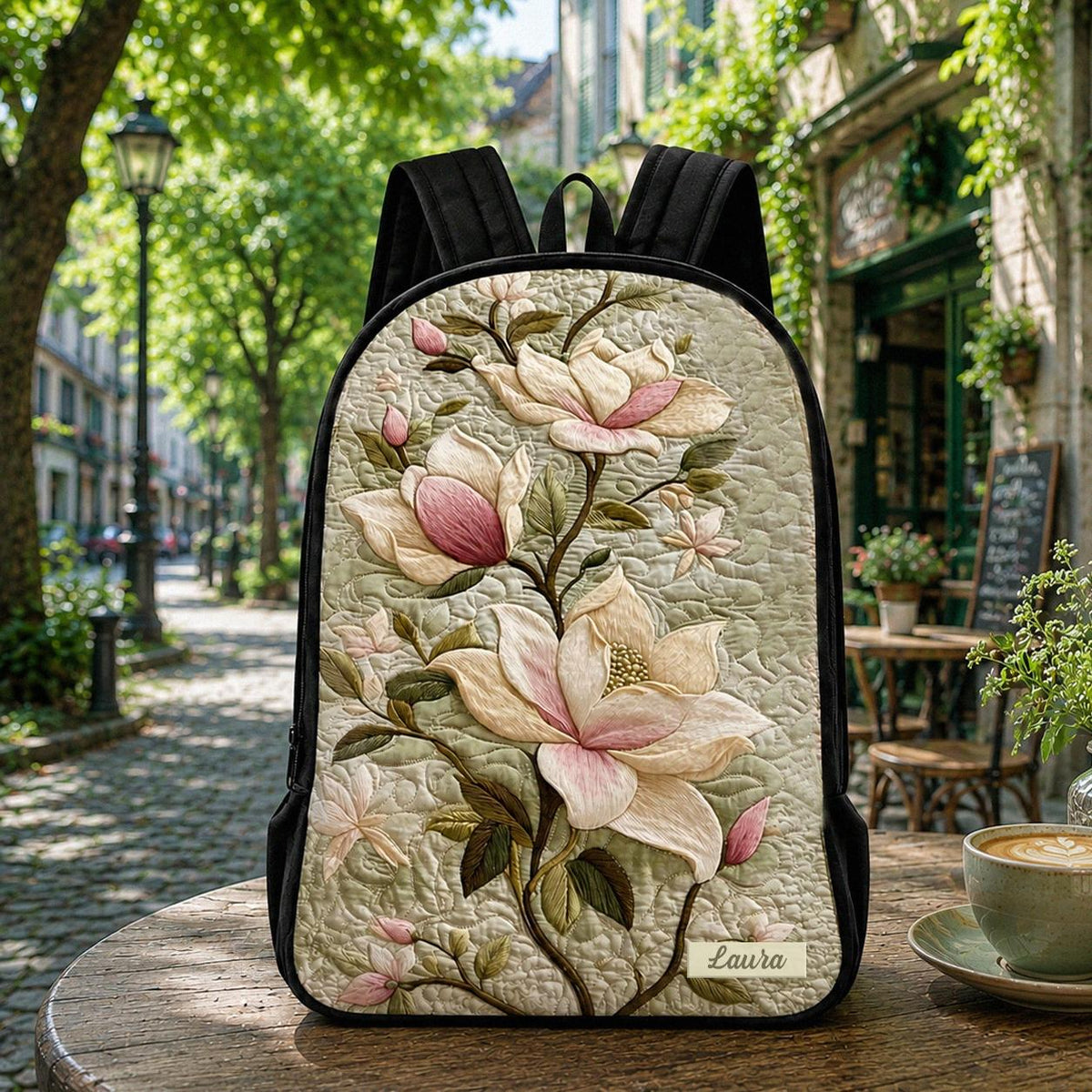 Artisan quilted backpack with broad magnolia blooms layered against dark green leaves across the front