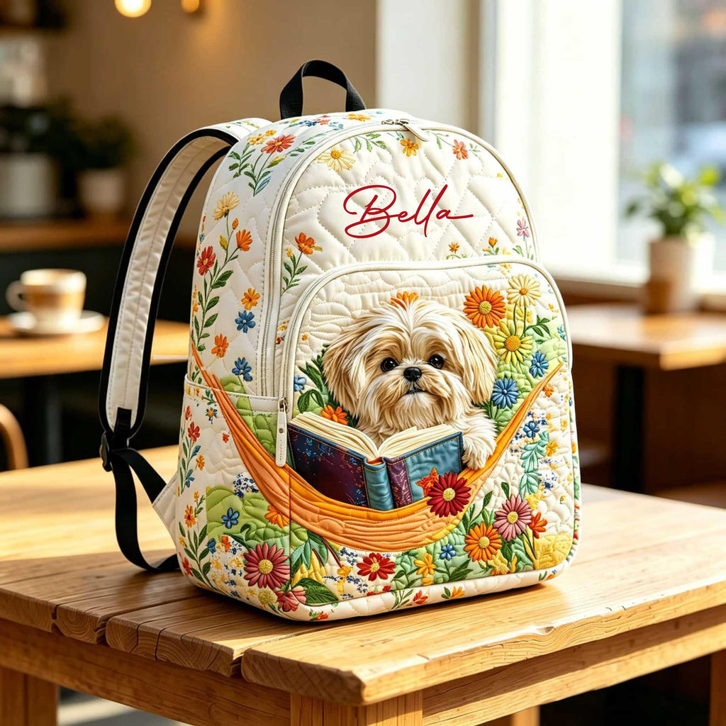 Artisan quilted backpack with a shih tzu reading an open book beside a stack of others
