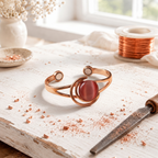 Magnetic copper bangle with a polished rose-red stone in a curved frame