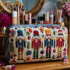 Quilted make-up bag with a nutcracker lit by warm amber and cream candlelight, snowflakes drifting in the darker background, in the Nutcracker Glow design