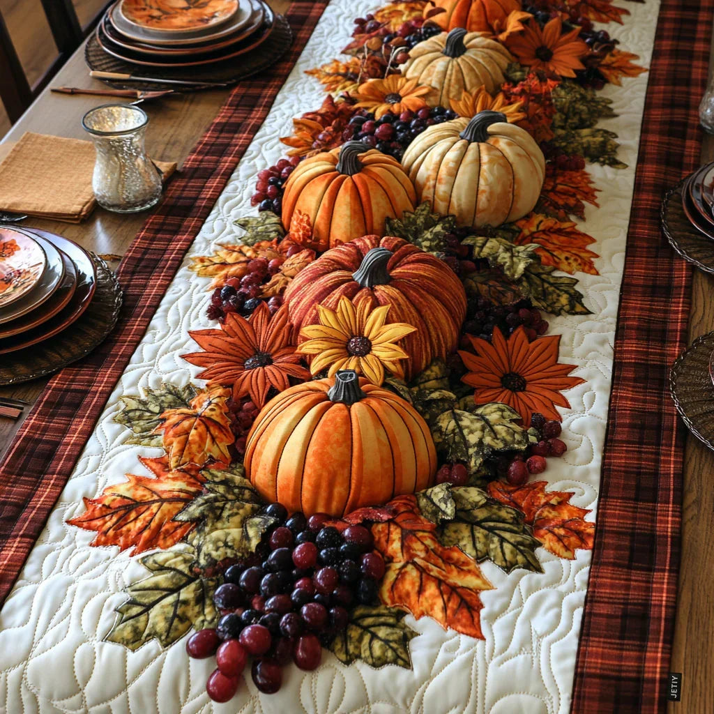 Quilted table runner with a row of orange pumpkins and pale ribbed squashes among autumn leaves