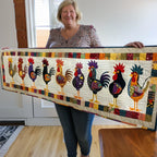 The Cockerel Parade quilted table runner laid down the centre of a kitchen table