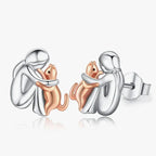 Silver and rose gold tone stud earrings of a woman hugging her cat
